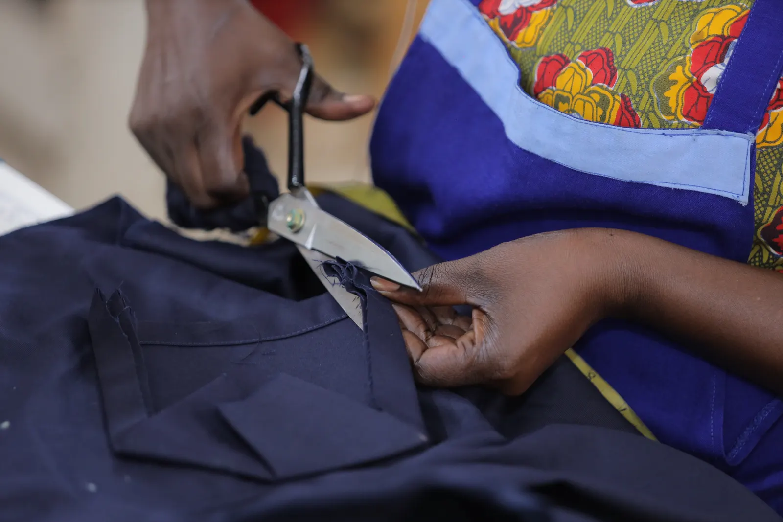 Garment maker cutting dark fabric with shears