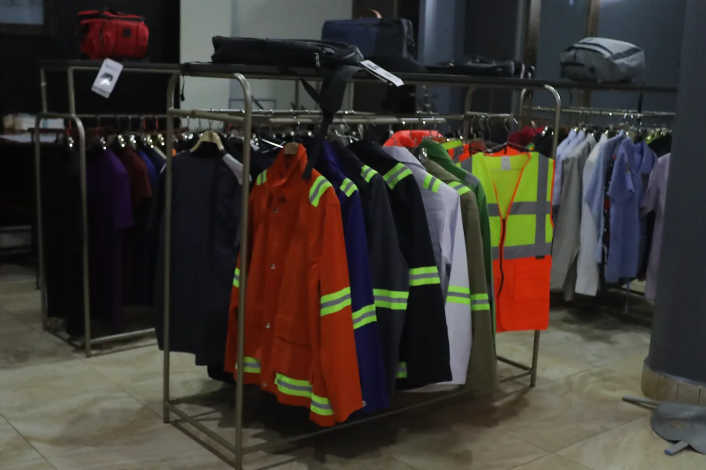 High-visibility overalls in several colours hanging on a rack