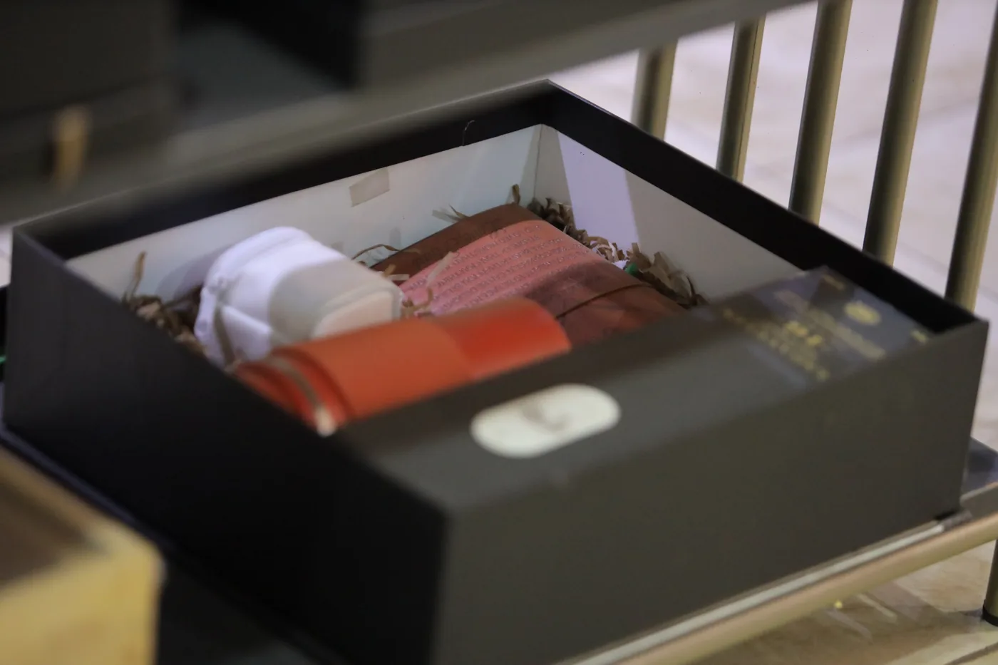 Open black presentation box containing assorted gifts