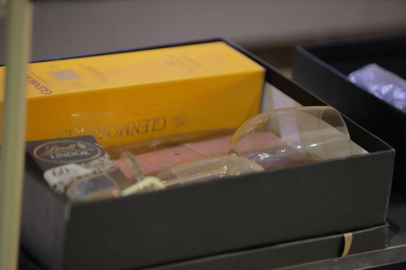 Open gift box with glassware and packaged treats